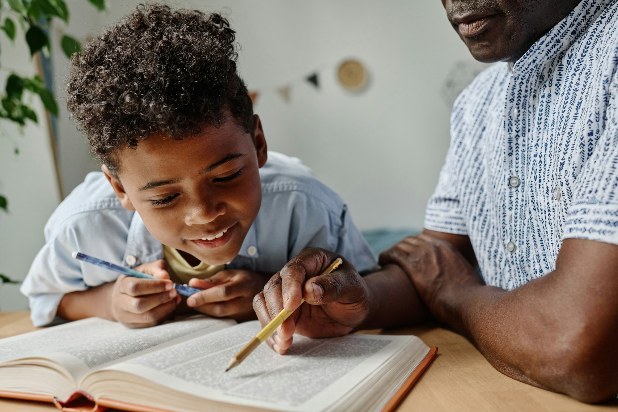 Boy reading book together with teacher